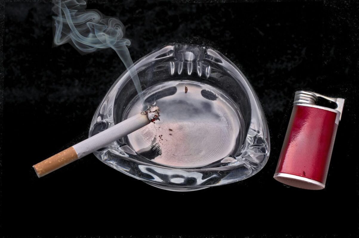 Image by NativeCigarettes.com Burning cigarette on an ashtray beside a red lighter